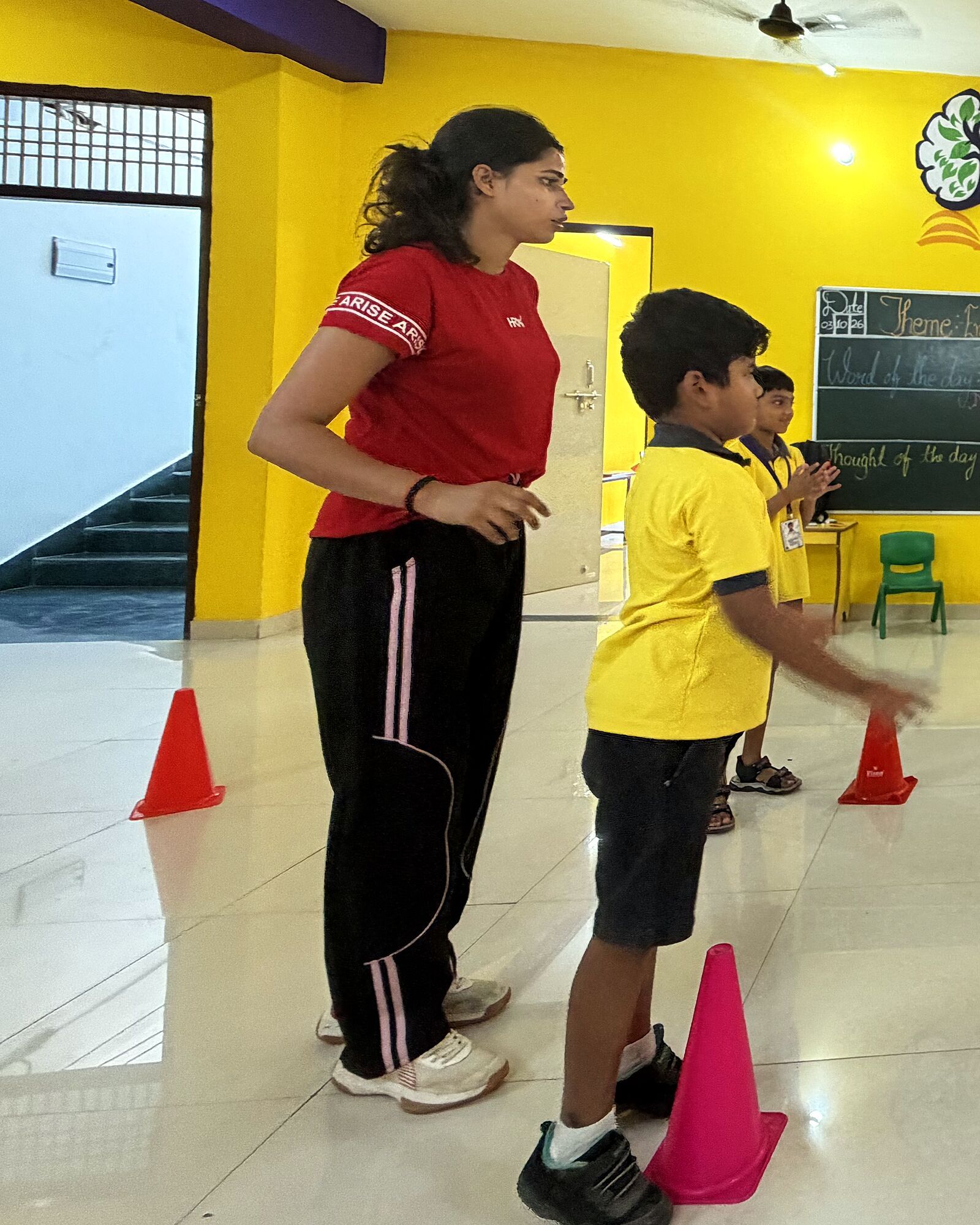 The visiting expert from BHU, in red, in the games hall beside a boy who has just passed the ball