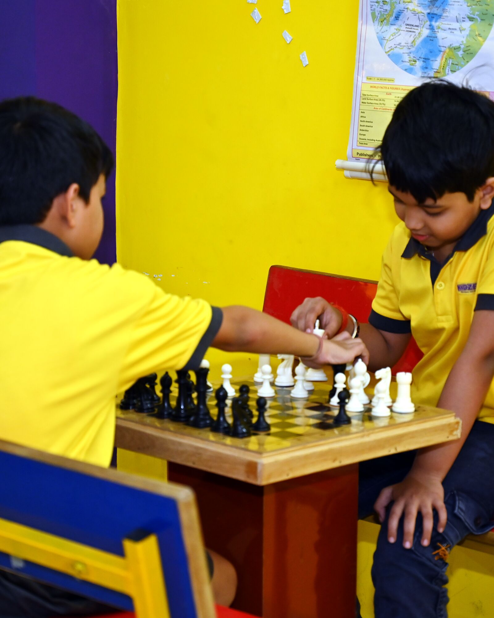 Two boys at a game of chess in the games room, one reaching to make his move