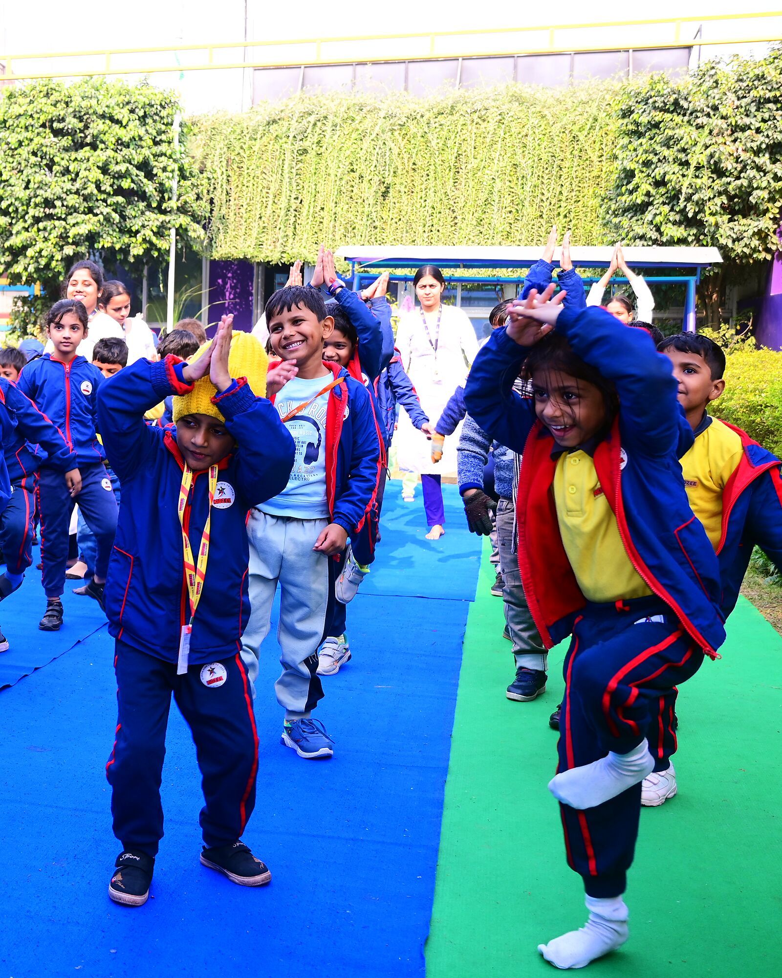 Children in tracksuits dancing Zumba on the mats, arms up