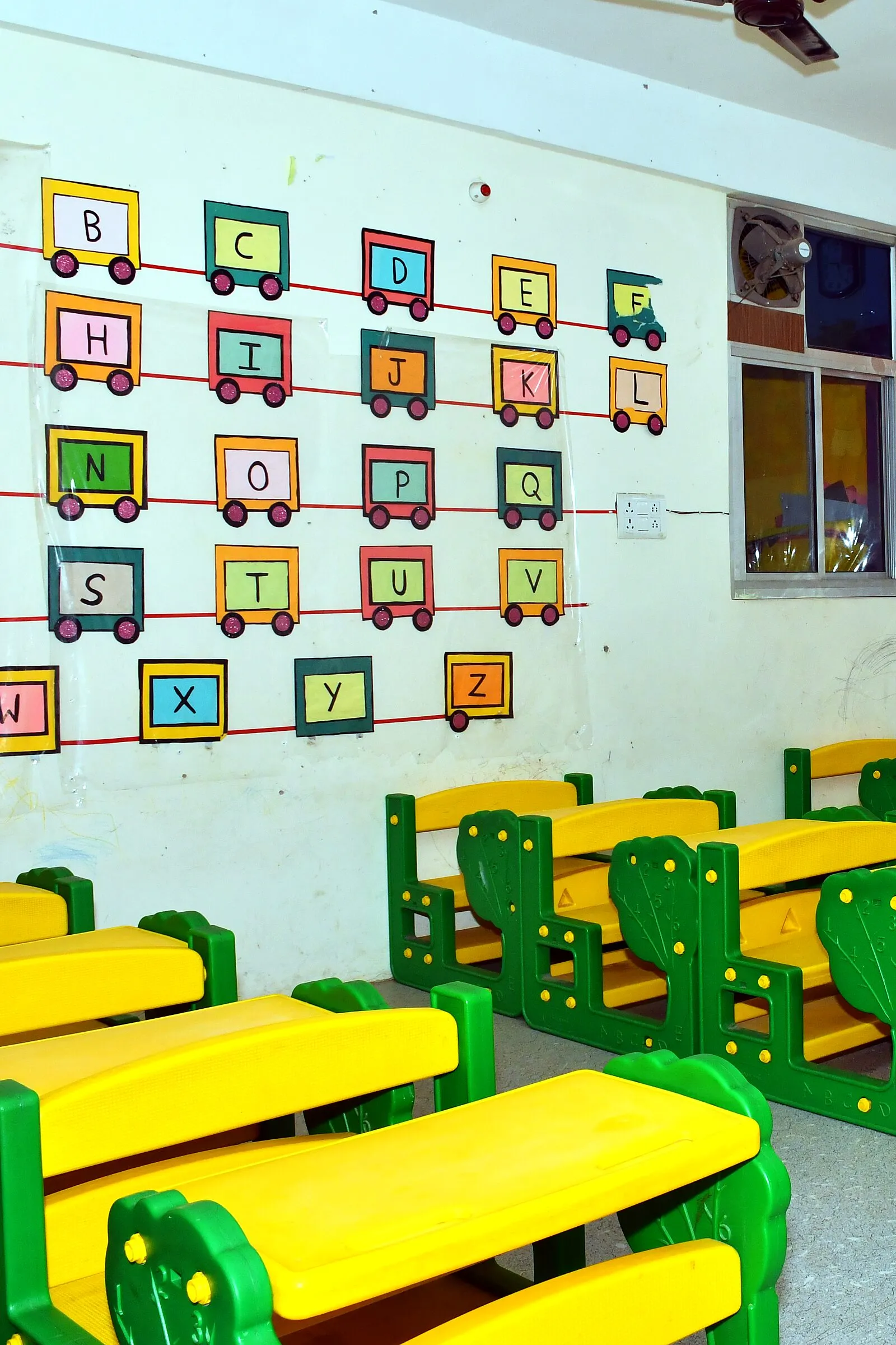 Children's work on a classroom wall above green benches