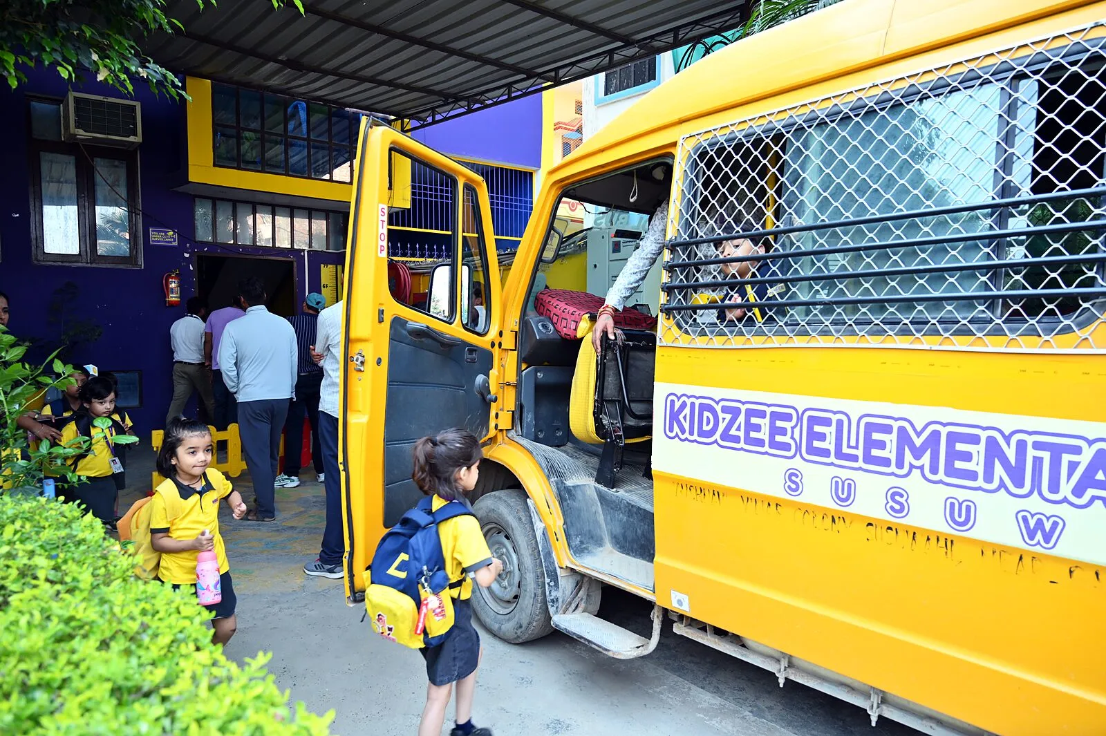 Children with their school bags walking out to the vans under the covered drive