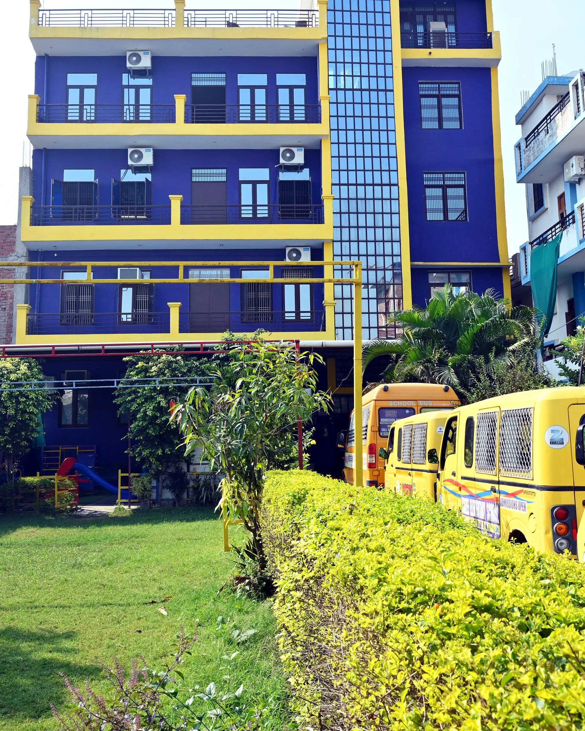 The school's vans parked by the hedge, the building above them