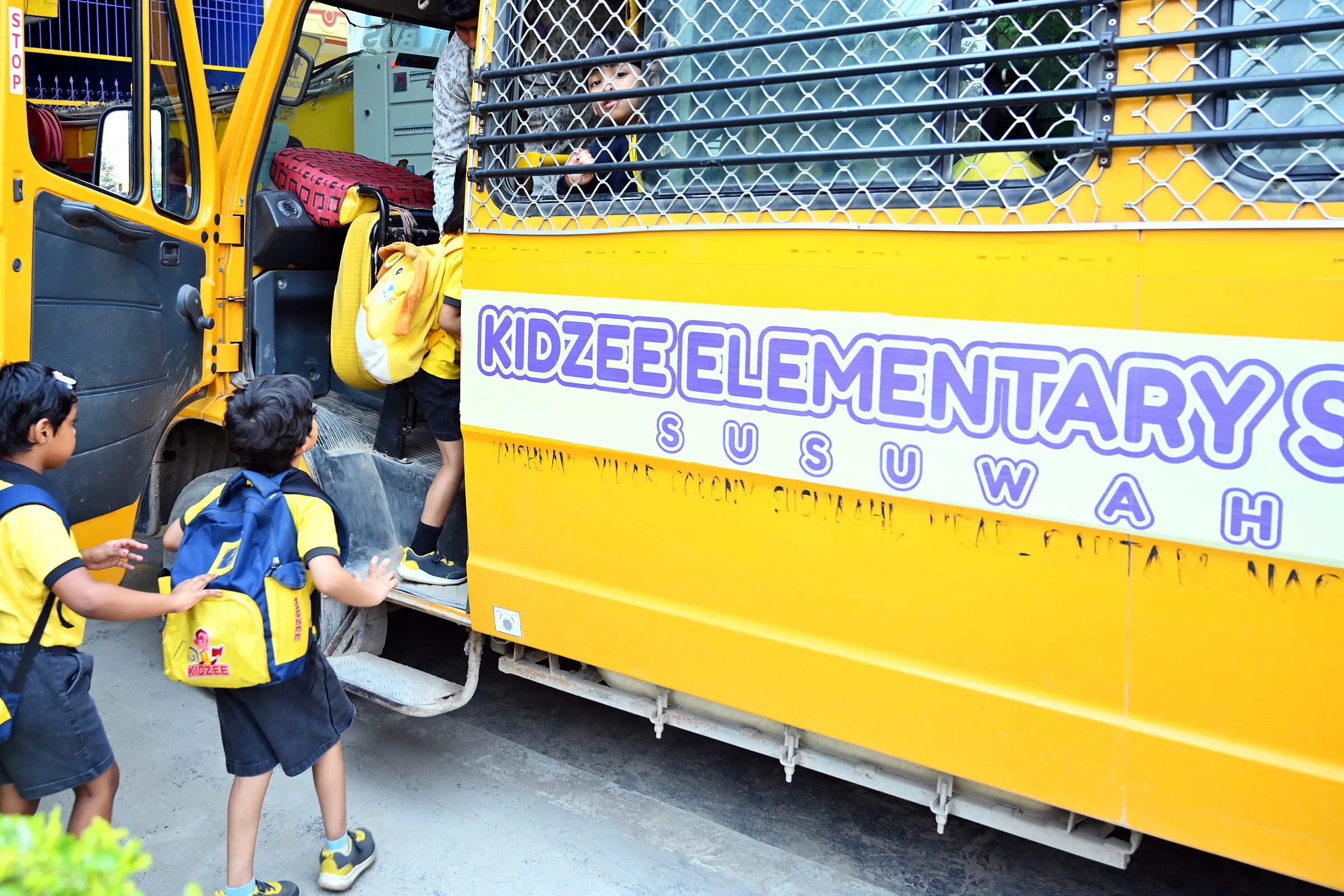 Children with school bags climbing into the school van from behind, a friend in the window