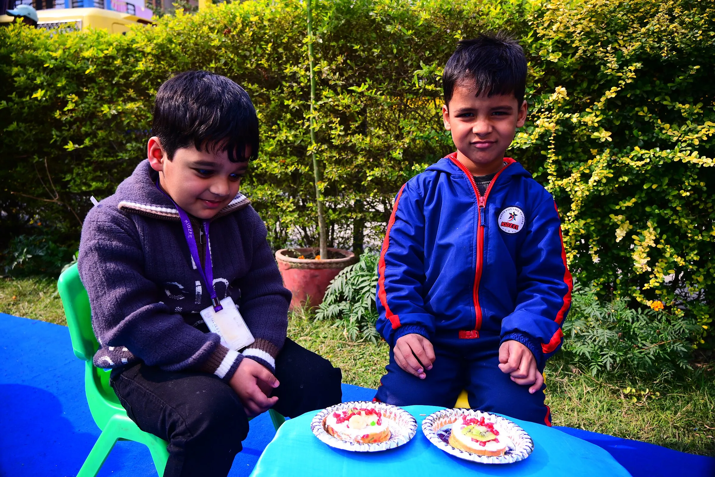 Two boys at a table on the lawn with plates of food