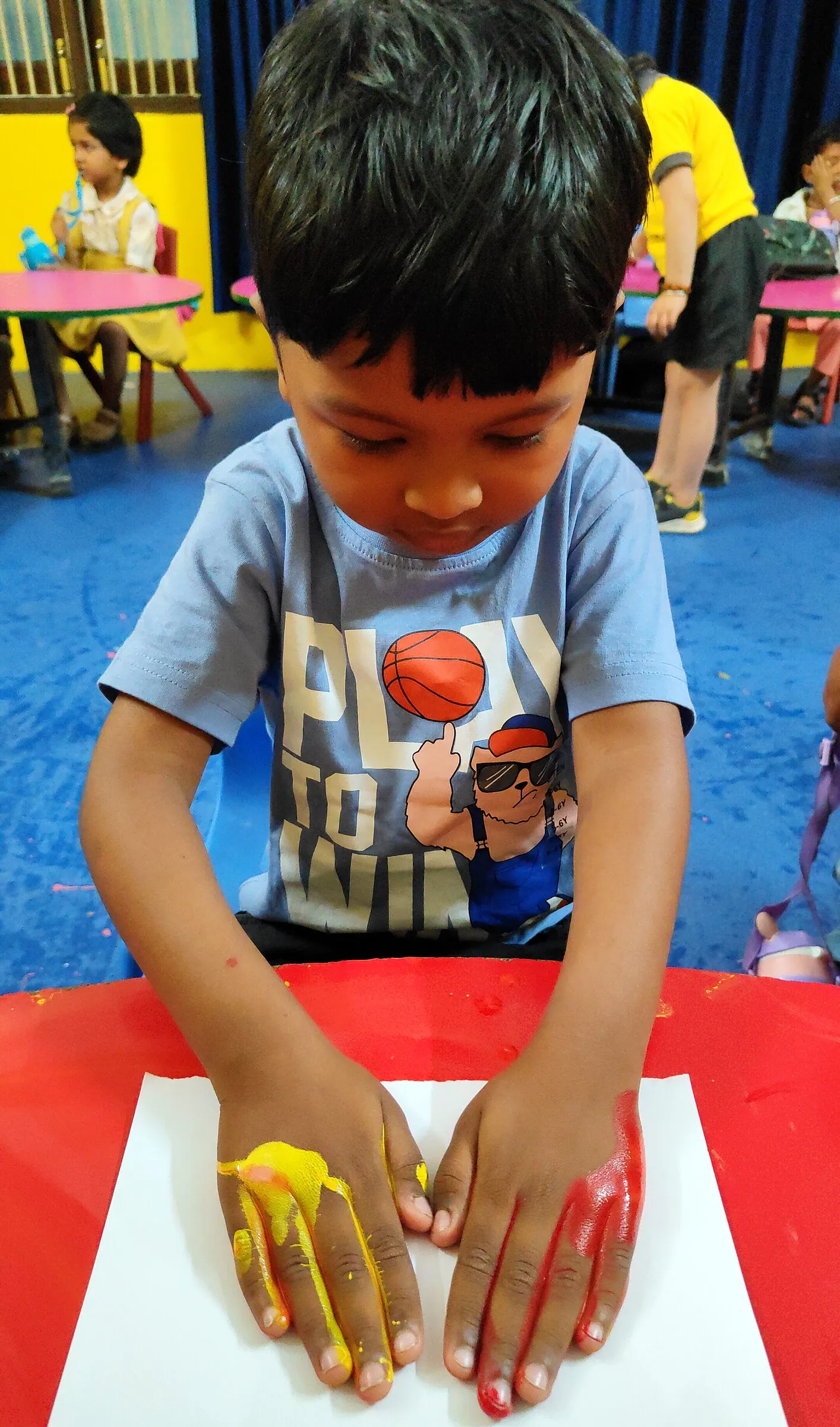A boy pressing his painted palms onto a sheet of paper