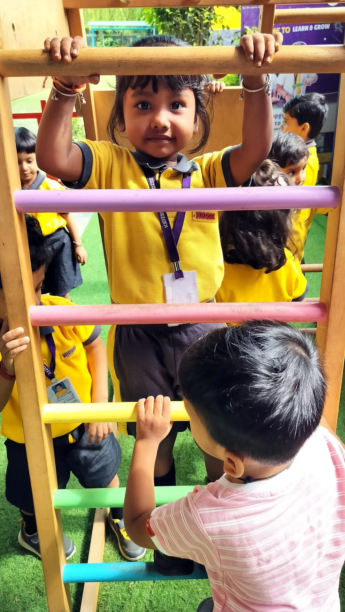 Children climbing a rainbow wooden ladder, one seen from behind
