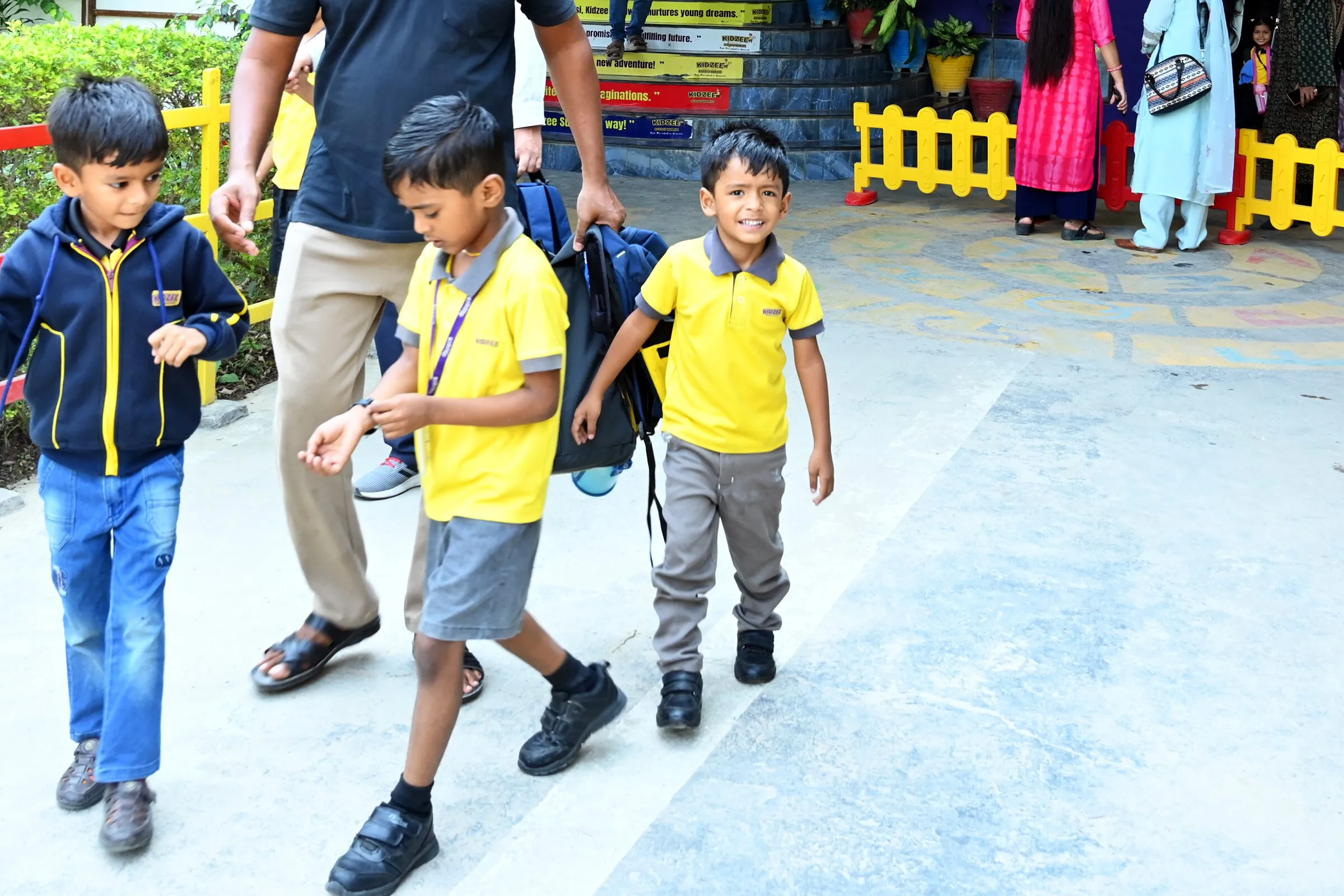 Three boys with their school bags walking out along the path at home time