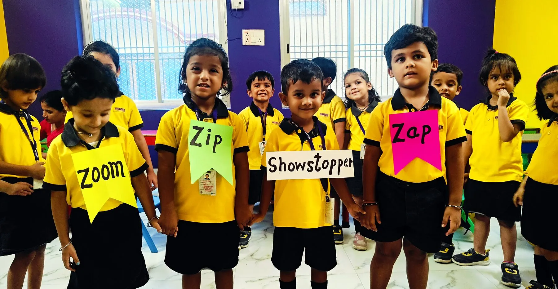 Children in uniform wearing big word cards: Zoom, Zip, Zap