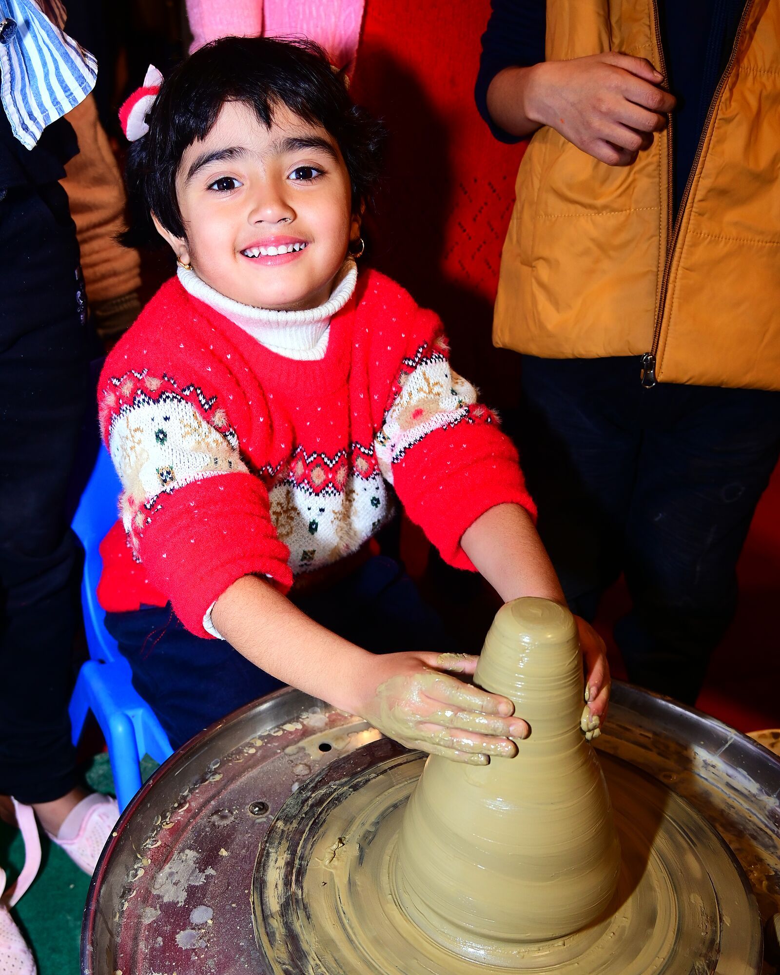 A smiling child shaping clay on a potter's wheel
